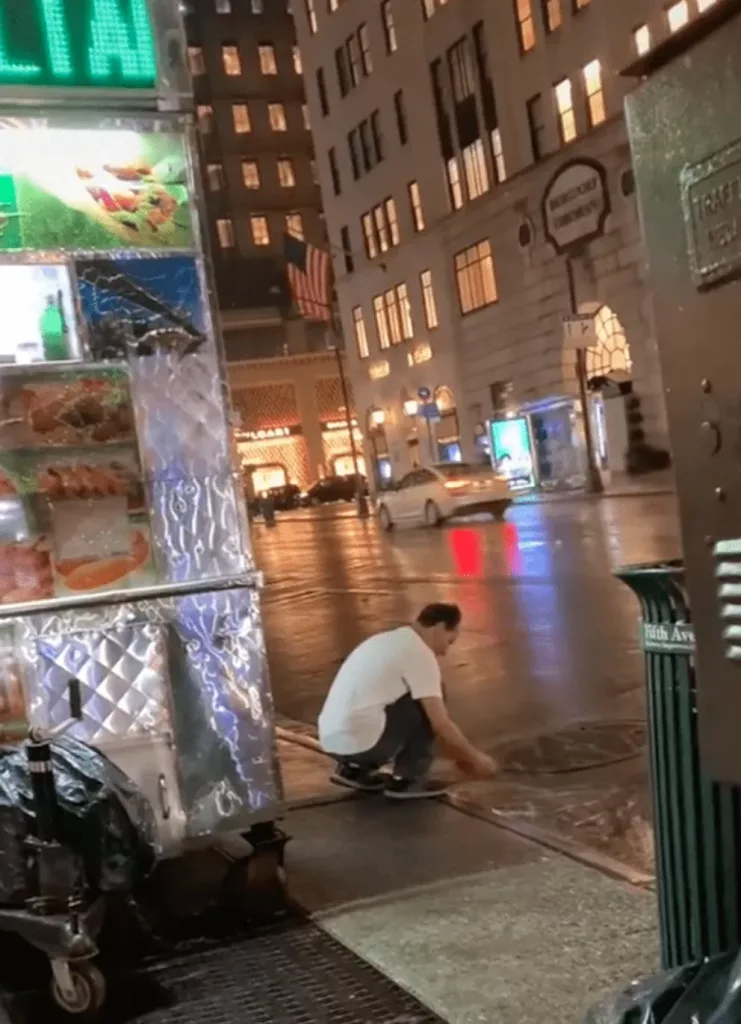 A street worker is filmed washing his laundry in a puddle of rainwater