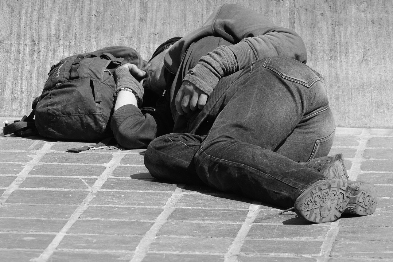 A homeless man lying on the side of the road. | Photo: Pixabay