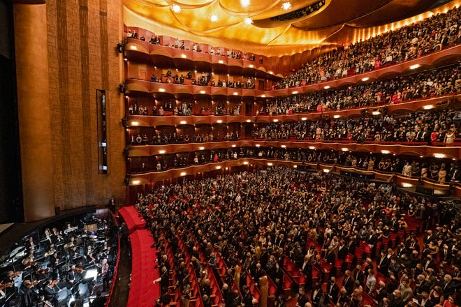 In this photo provided by the Metropolitan Opera, the audience stands for the national anthem before the performance of Terence Blanchard's "Fire Shut Up in My Bones," which opened the Metropolitan Opera's 2021-2022 season.