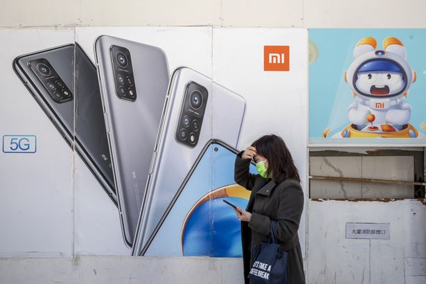 A pedestrian walks past advertisements at a Xiaomi Corp. store, with a boarded up shopfront in place since protests last year, in Hong Kong, China, on Wednesday, Dec. 2, 2020. Xiaomi dropped the most ever in Hong Kong after China's No. 2 smartphone maker raised $3.1 billion in the city's biggest top-up placement on record. Photographer: Paul Yeung/Bloomberg via Getty Images