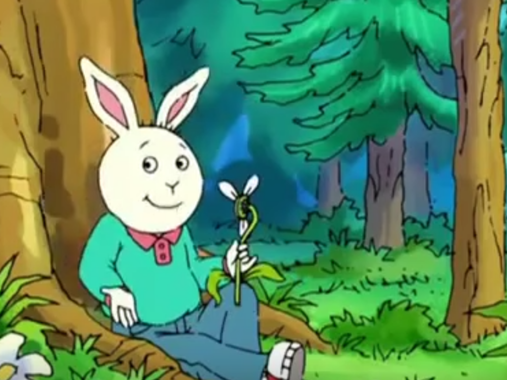 Buster Baxter sitting against a tree, holding a flower