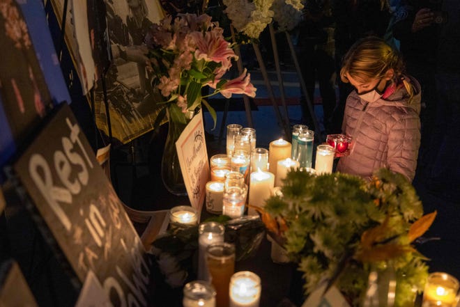 A girl pays respects near a photo of cinematographer Halyna Hutchins, who was killed by a prop gun fired by actor Alec Baldwin, at a memorial table during a candlelight vigil in her memoryon Oct. 24, 2021.