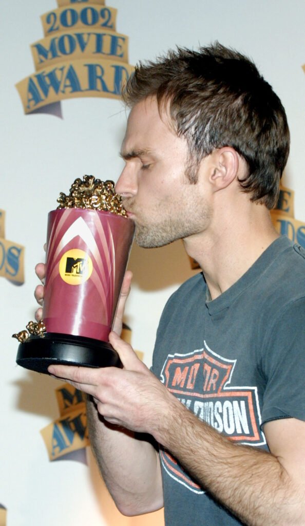 Seann William Scott kisses his MTV Movie Award. He is wearing a Harley-Davidson tee shirt.