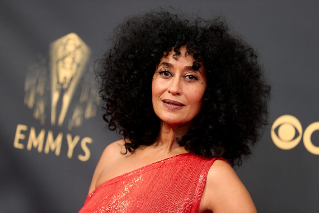Tracee Ellis Ross wearing one-shoulder red gown against black backdrop