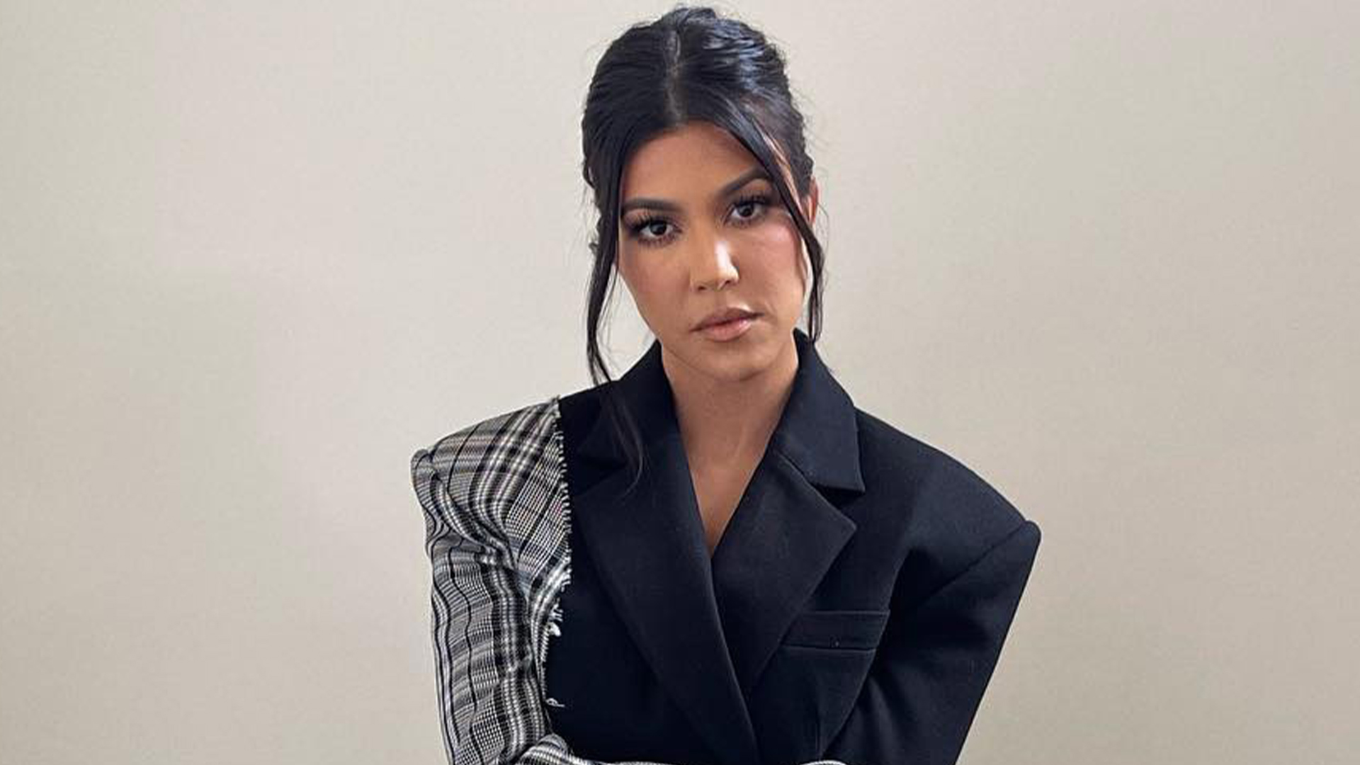 Kourtney Kardashian covers her stomach in an oversized blazer as she appears to be pregnant with her fourth child, according to a new photo.